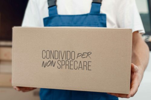 Deliveryman with carton box at the car, delivery service. Man in uniform holding cardboard package, male deliver, courier job